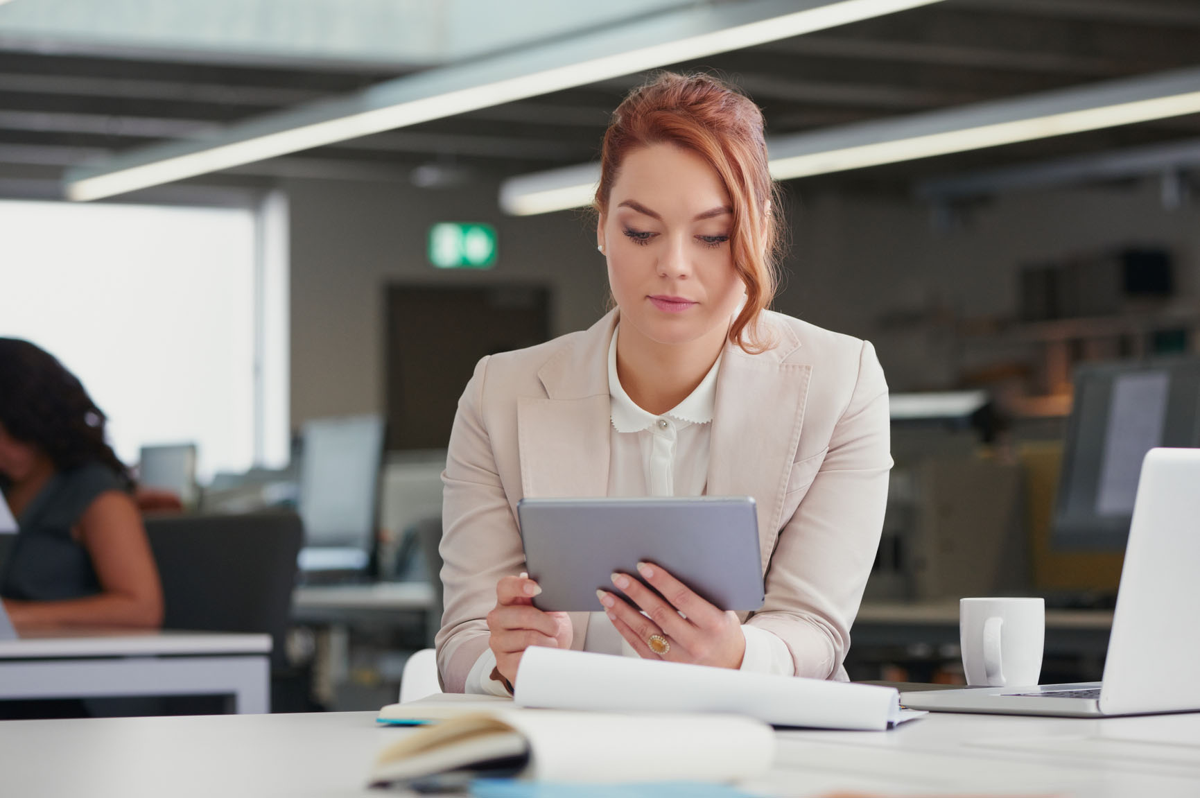 Woman in an office looking at a tablet.