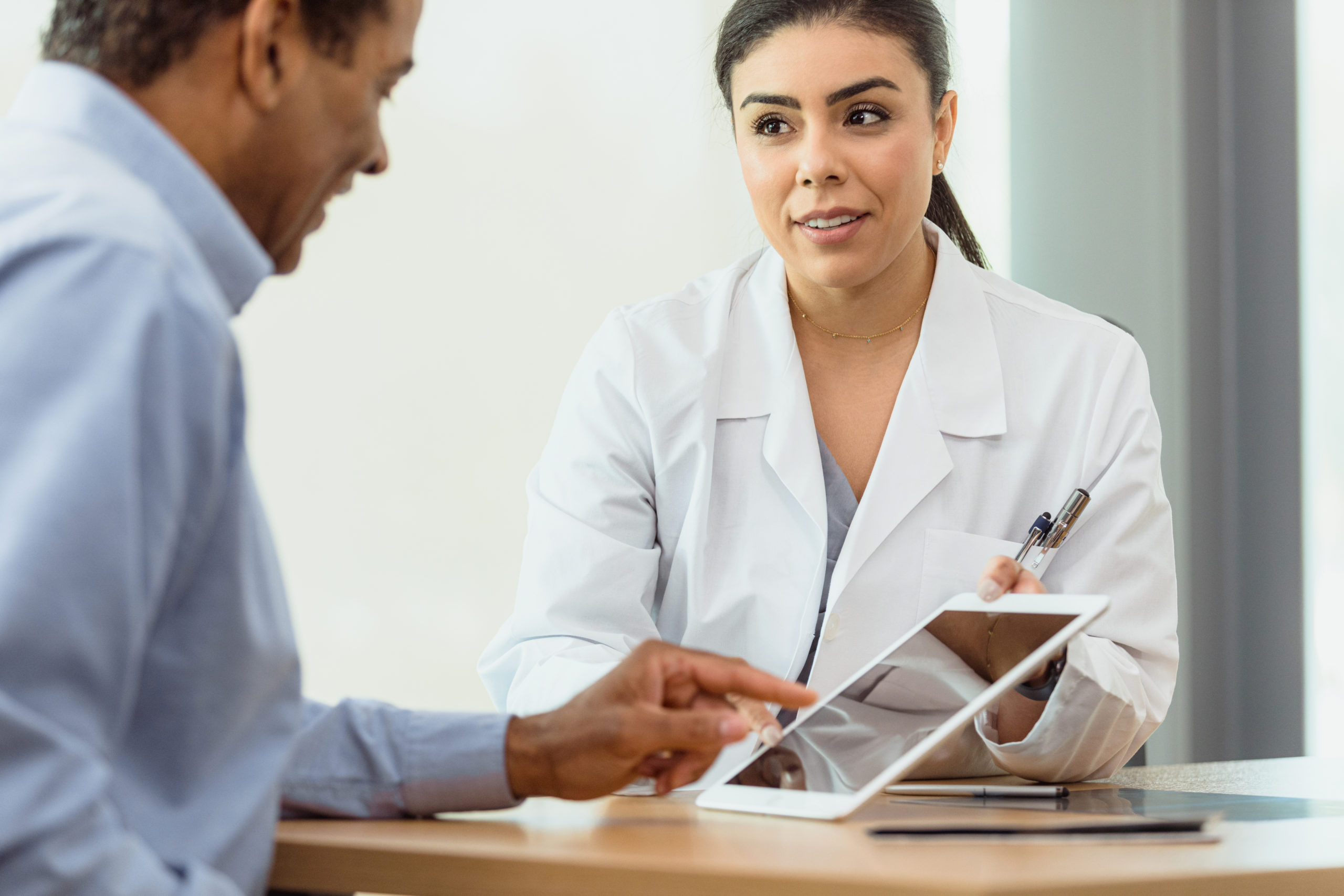 A mature male patient signs a medical form on a digital tablet.