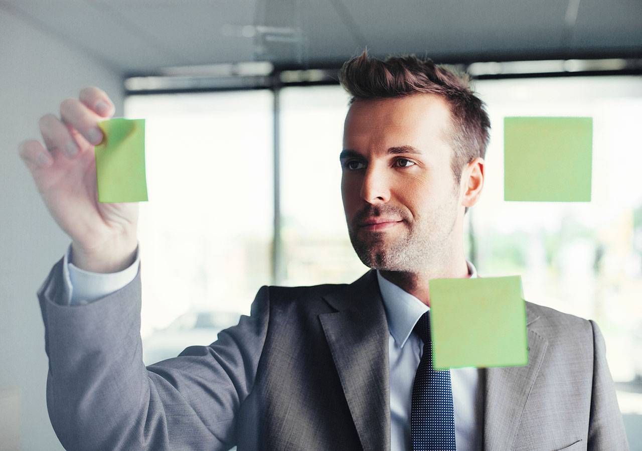 business man placing sticky notes on glass to outline employee and customer experience improvement framework