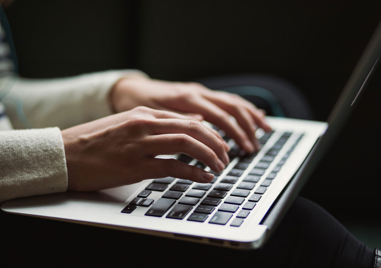 Two hands typing on a laptop