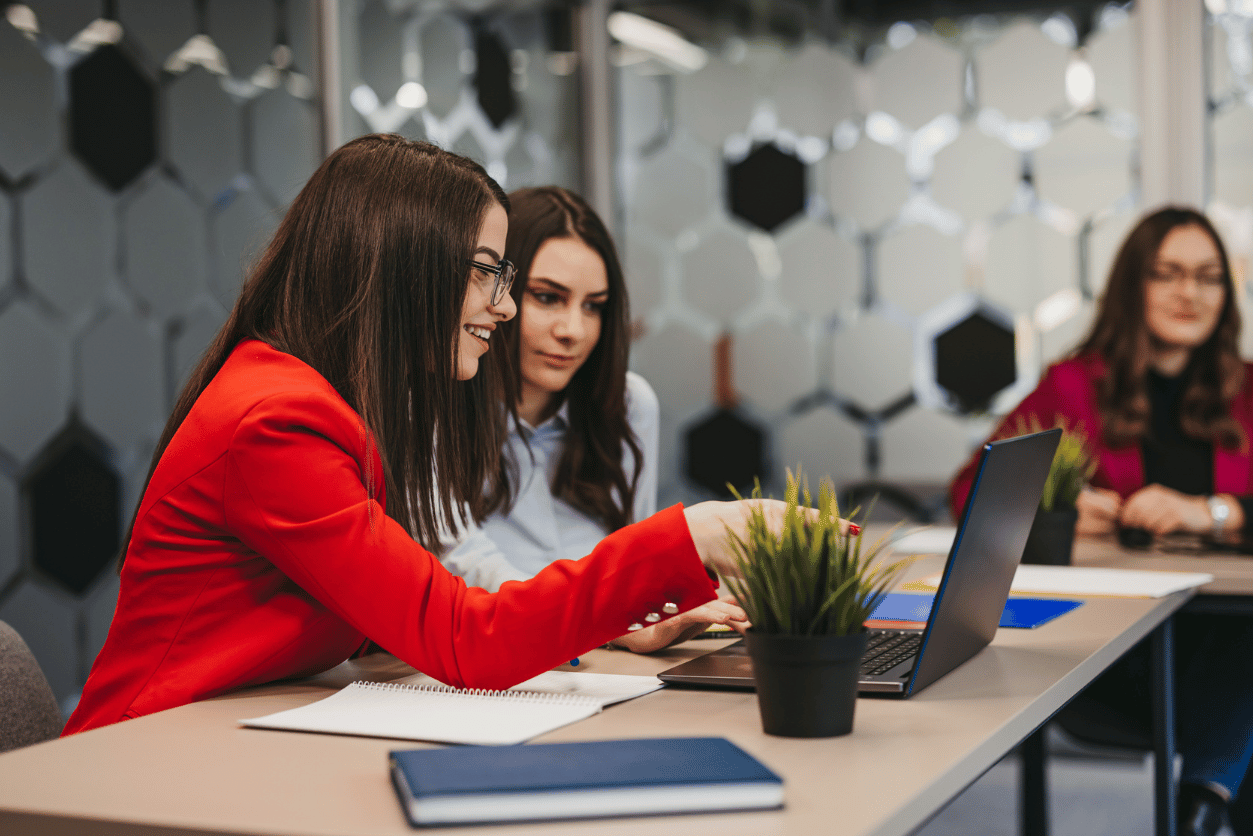 Metro Bank + InMoment: image of two women sitting at a desk looking at a computer in an office setting