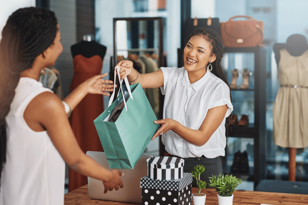 Primark + InMoment customer story - image of a woman behind a shopping counter handing another woman a shopping bag